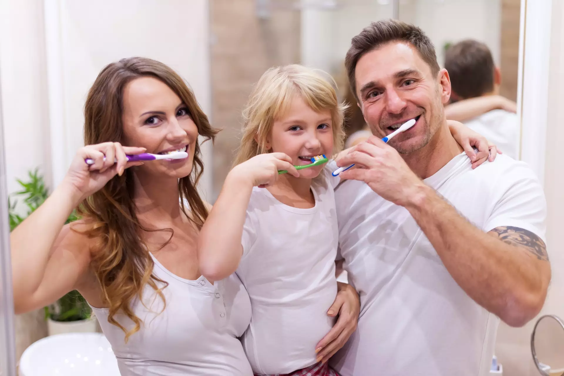 Mujer, niña y hombre lavándose los dientes